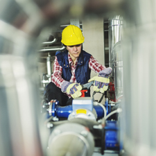 In a utility or factory one technician is working on a valve on building technical equipment or industrial site.